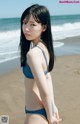 A woman in a blue bikini standing on a beach.