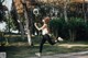 A woman in a white top and black leggings running in a park.