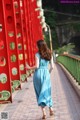 A woman in a blue dress walking across a bridge.