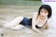 A woman in a black bathing suit laying in the water.