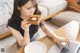 A woman sitting at a table eating a piece of bread.