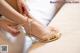 A woman is putting on a pair of gold shoes.