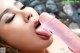 A woman is sucking a pink dildo in her mouth.