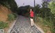 A woman in a red shirt and black skirt walking down a path.